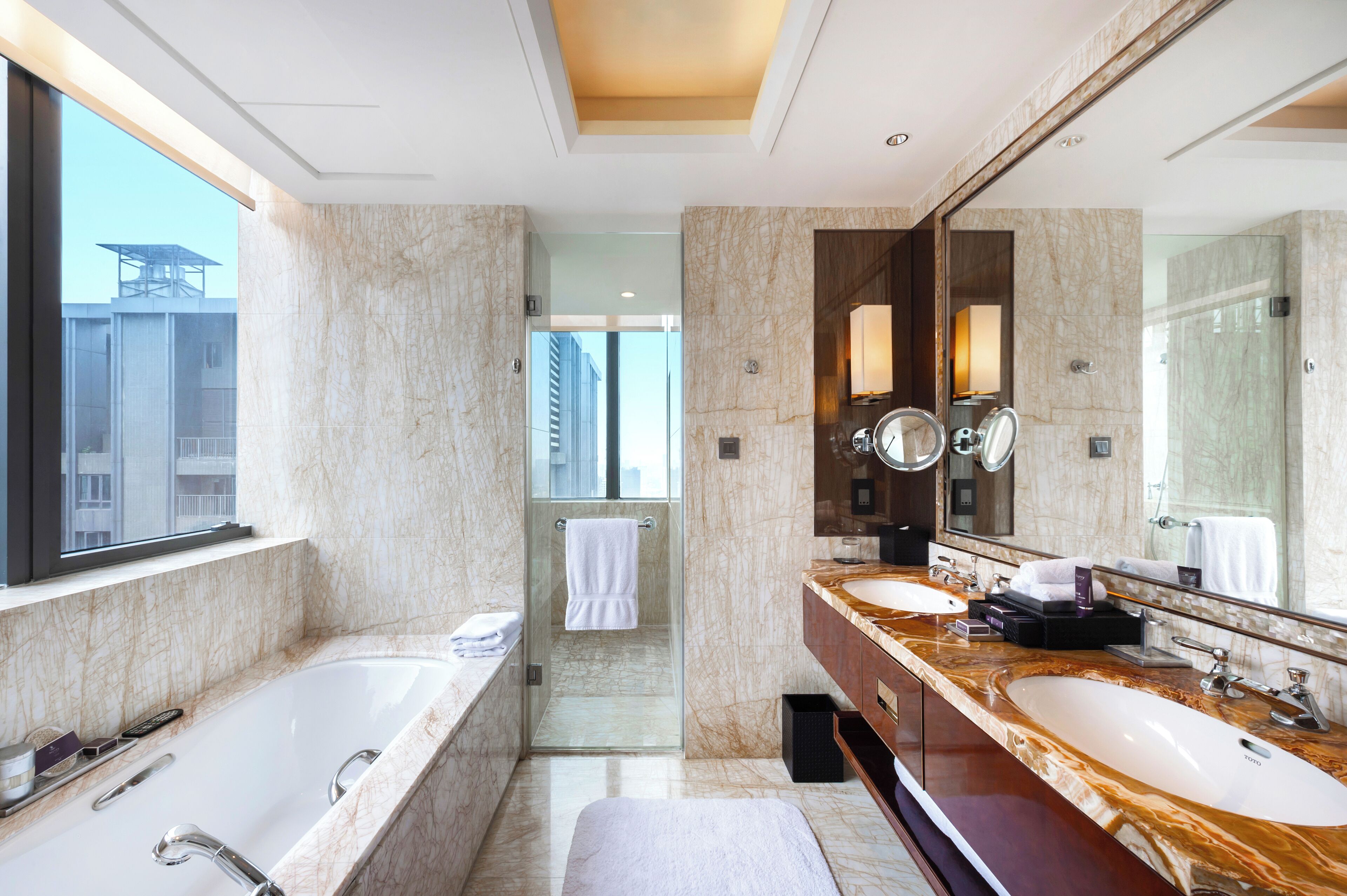 Een moderne badkamer met twee wasbakken, een grote spiegel en een douche met glazen wanden.