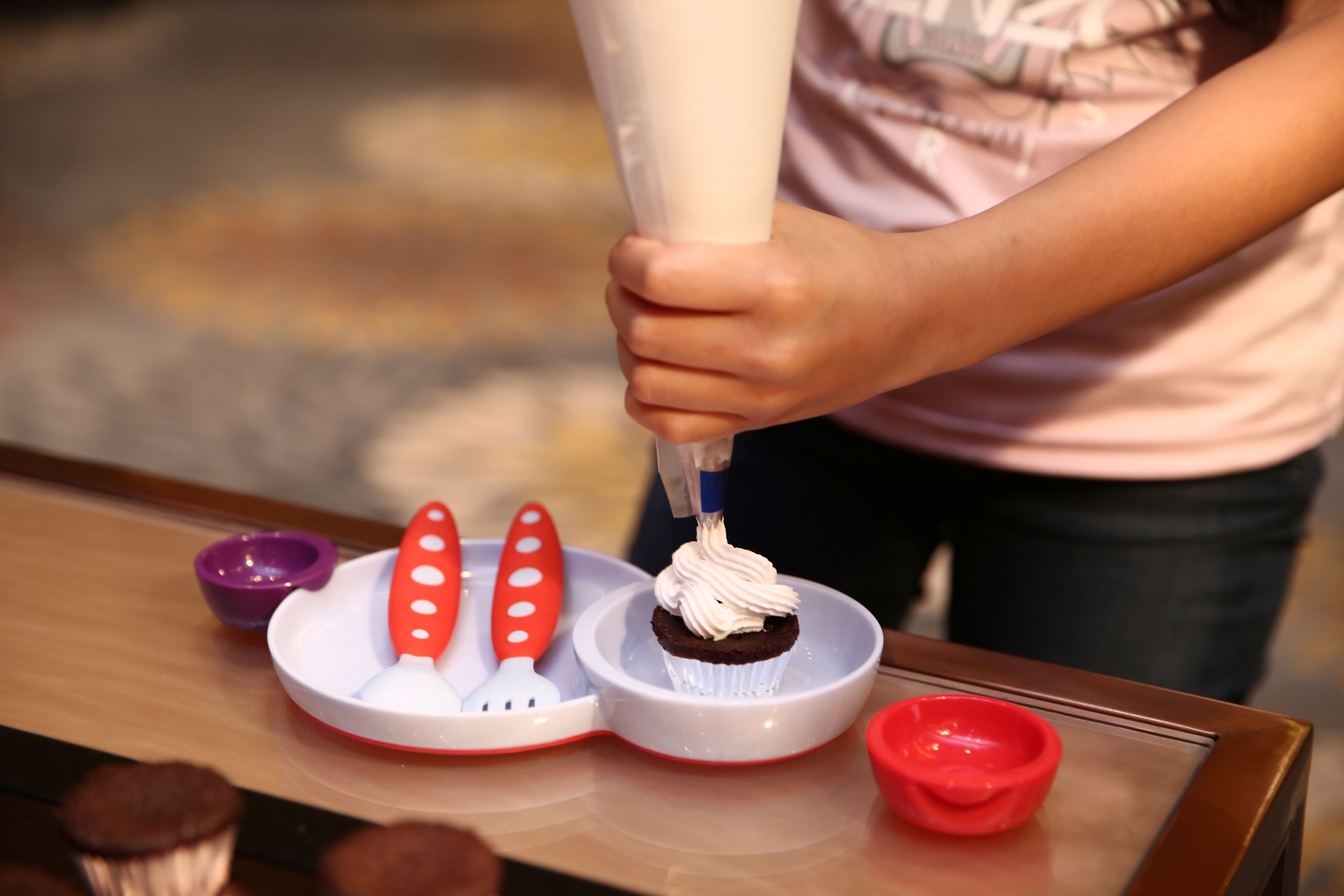Une personne utilise une poche à douille pour décorer un petit gâteau.