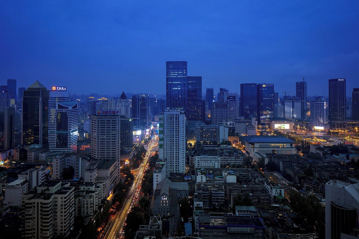 A cityscape at dusk with high-rise buildings and a busy street.