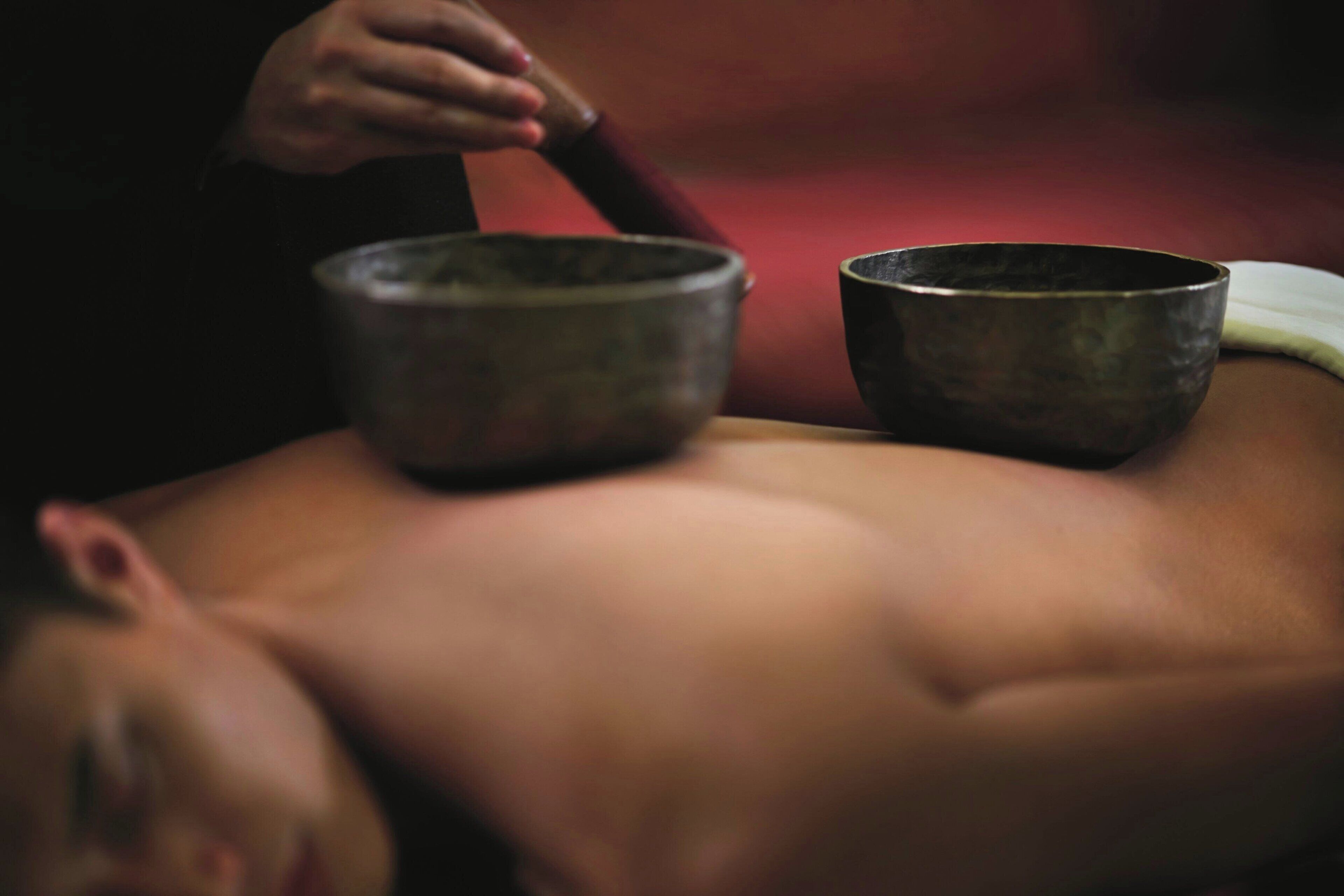 A person lying down with two bowls placed on their back.