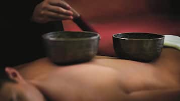 A person lying down with two bowls placed on their back.
