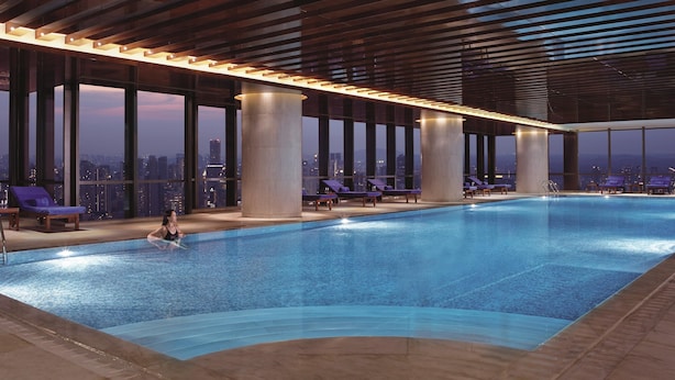 An indoor swimming pool with a city view, large pillars, and lounge chairs. - The Ritz-Carlton, Chengdu (Chengdu)
