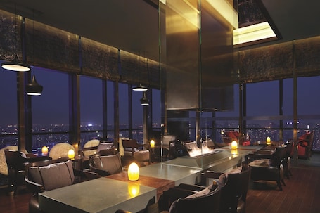A modern restaurant with high ceilings, large windows, and a city view.