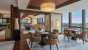 Interior moderno de hotel con zona de comedor, cocina y grandes ventanales con vistas a la ciudad.