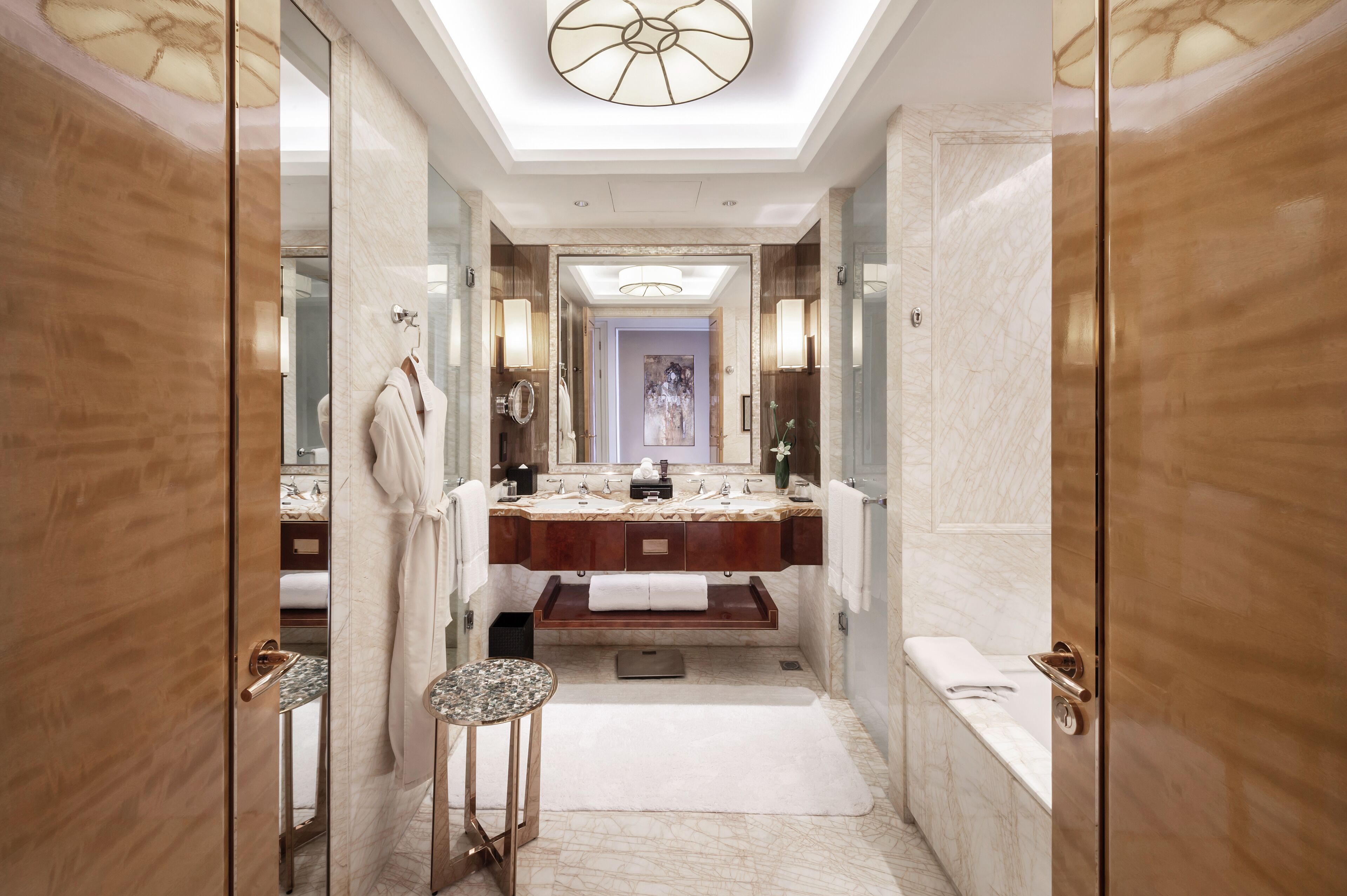 A luxurious bathroom with a marble vanity, a large mirror, and a modern chandelier.