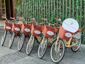 A row of bicycles with baskets labeled "The Ritz-Carlton Chengdu" parked against a wall with vertical greenery.