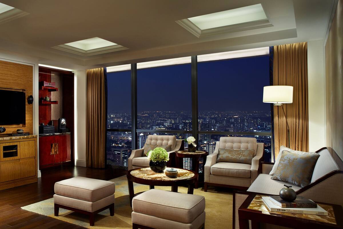 Un salon spacieux avec vue sur la ville, une télévision et un mini-bar rouge.