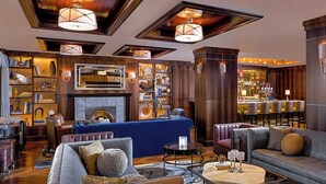 A well-lit, modern lounge area with a fireplace, plush seating, and a bar with a variety of bottles. - WestHouse Hotel New York, an SLH Hotel (New York)