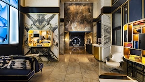 A modern lobby with a marble floor, a reception desk, a seating area, and a bookshelf. - Le Meridien New York, Central Park by Marriott (New York)