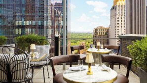 A rooftop terrace with outdoor seating, a view of the cityscape, and modern buildings in the background. - Le Meridien New York, Central Park by Marriott (New York)