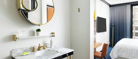A hotel bathroom with a marble sink, gold fixtures, and a large mirror.