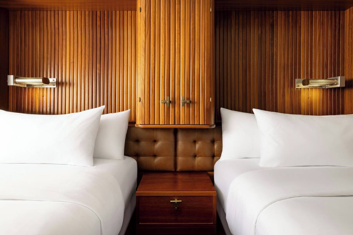 Ein Hotelzimmer mit zwei Betten, Holzwandverkleidung und einer zentralen Kommode.