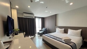 Una habitación de hotel con cama, escritorio, televisor y aire acondicionado.