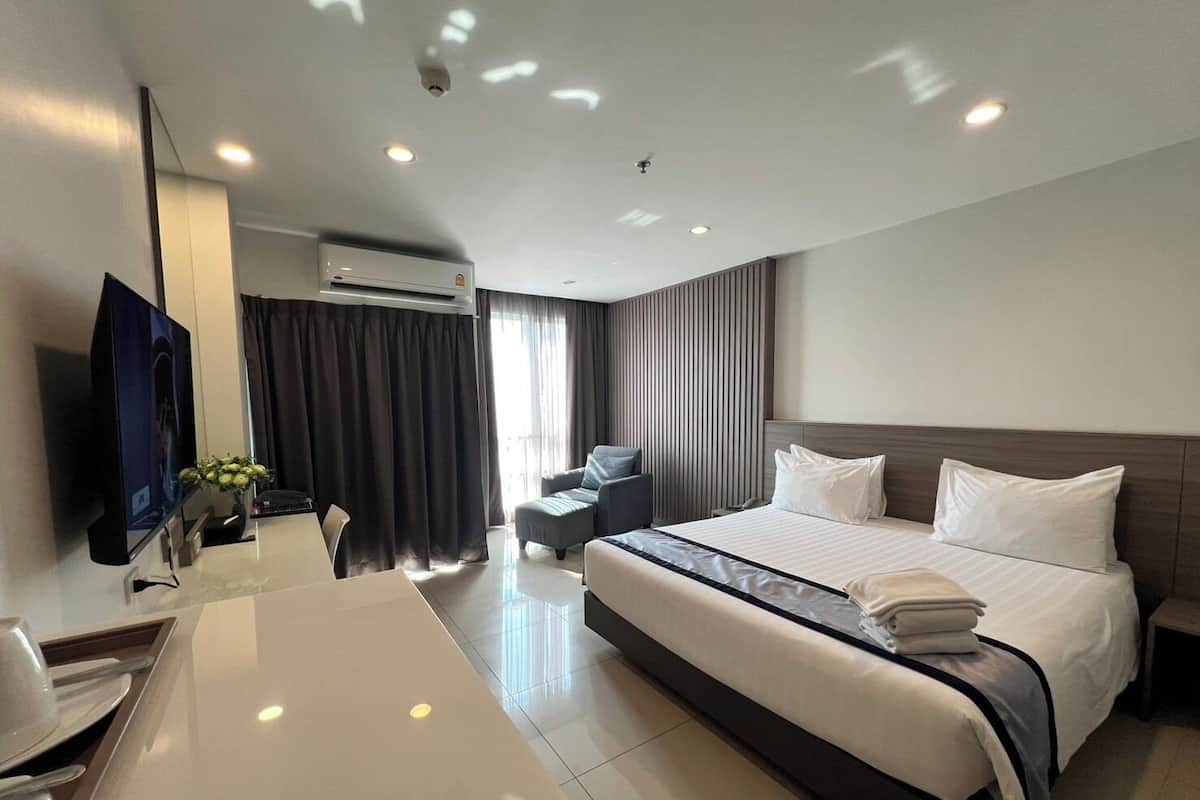 Una habitación de hotel con cama, escritorio, televisor y aire acondicionado.