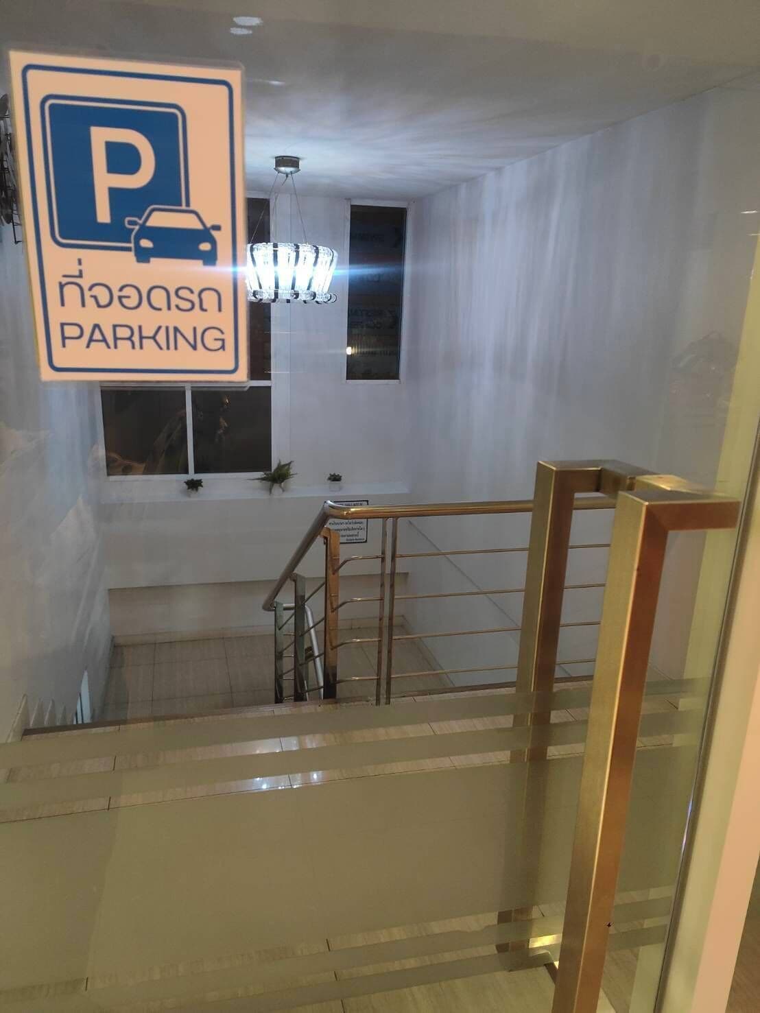 Una escalera con barandilla de metal, un cartel de estacionamiento y un candelabro.