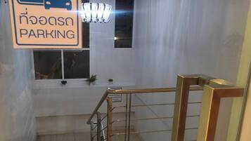 Una escalera con barandilla de metal, un cartel de estacionamiento y un candelabro.