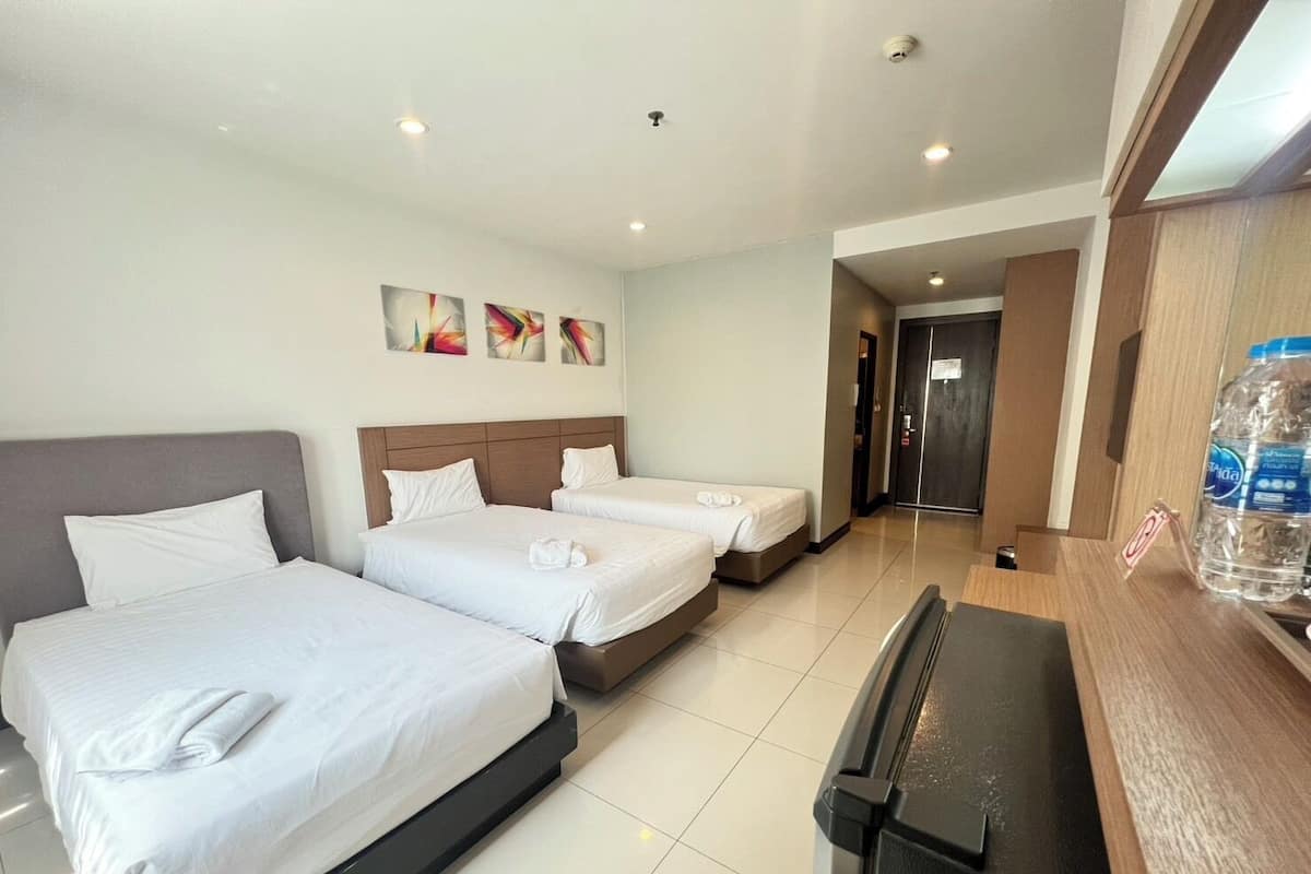 Habitación de hotel con dos camas, un escritorio y dispensador de agua.