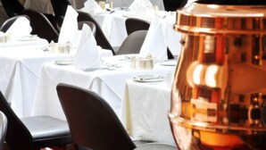 A dining area with tables set for service, black chairs, and a copper-colored decorative object. - Stafford Hotel (St. Helier)