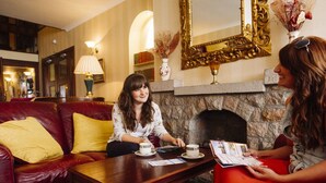A room with a stone fireplace, a red leather sofa, and a wooden coffee table. - Stafford Hotel (St. Helier)