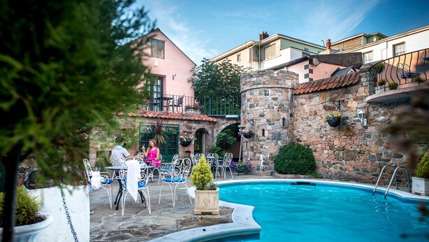 A pool area with stone walls, outdoor seating, and a clear blue pool. - Stafford Hotel (St. Helier)