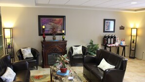 A lobby with leather sofas, a coffee table with a plant, framed artwork on the walls, and a fireplace. - Suburban Studios Triadelphia - Wheeling at The Highlands (Triadelphia)