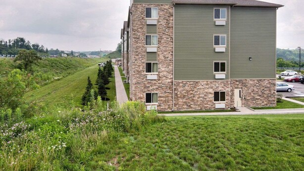 A Suburban Extended Stay Hotel with a stone facade and multiple windows. - Suburban Studios Triadelphia - Wheeling at The Highlands (Triadelphia)