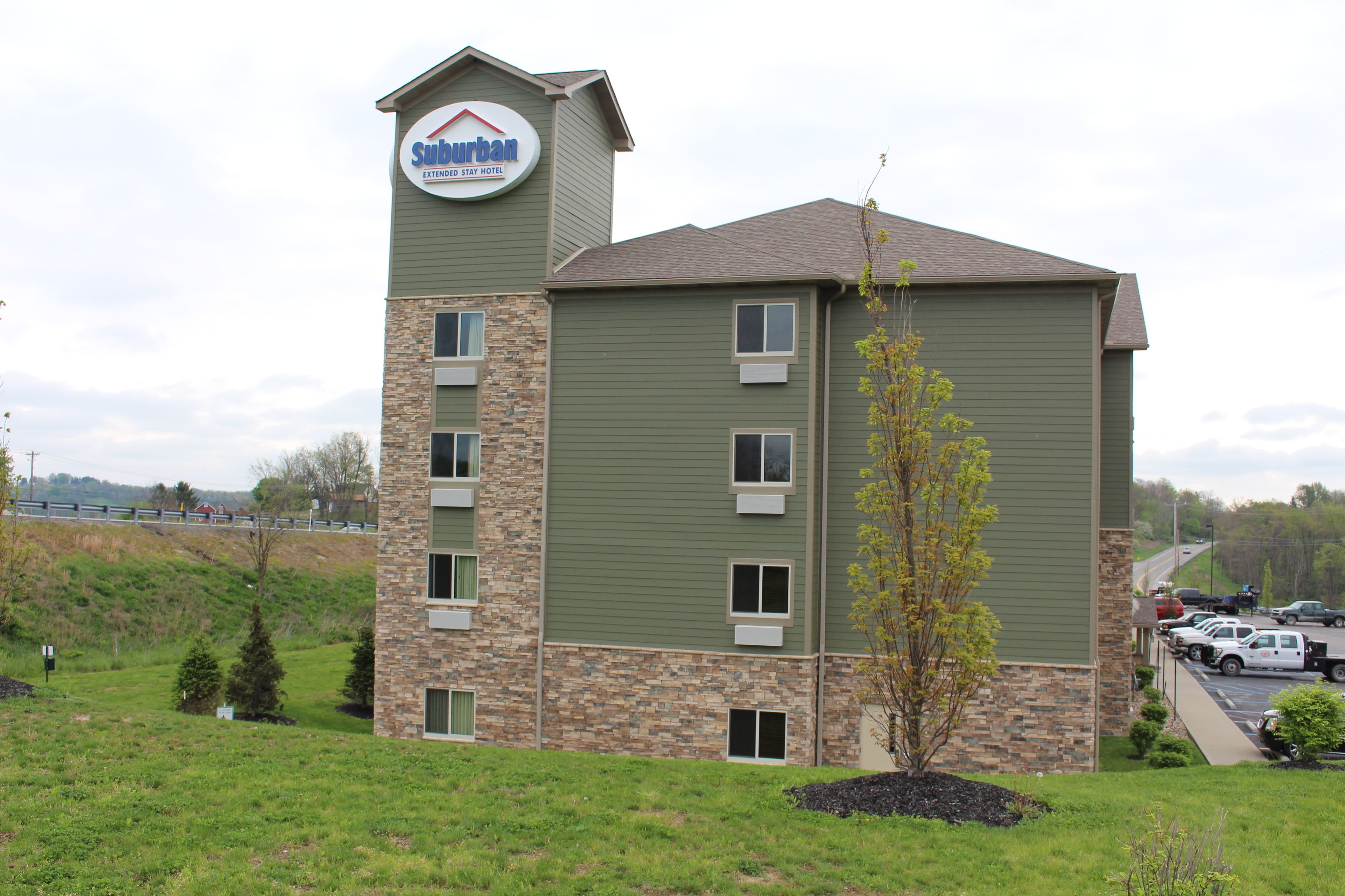 A Suburban Extended Stay Hotel with a stone facade, multiple windows, and a parking lot.