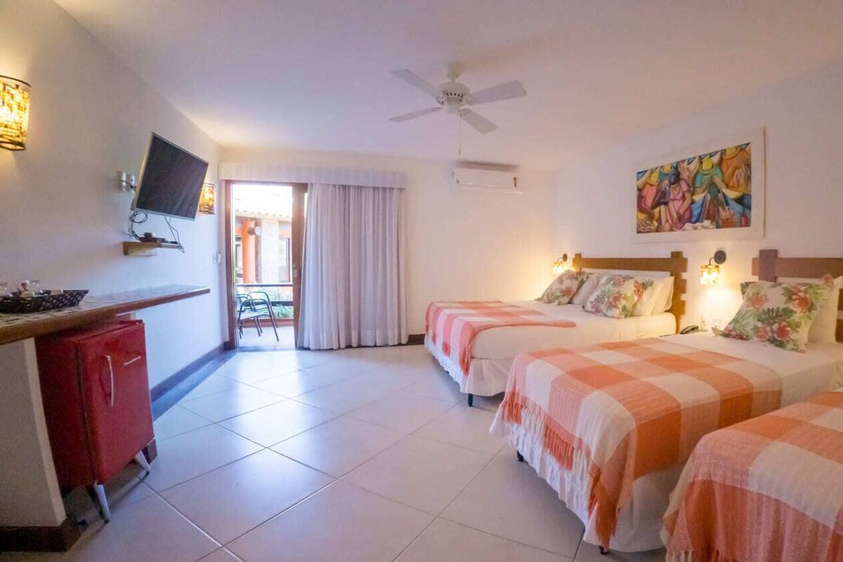 A hotel room with two beds, a desk, a TV, and a ceiling fan.
