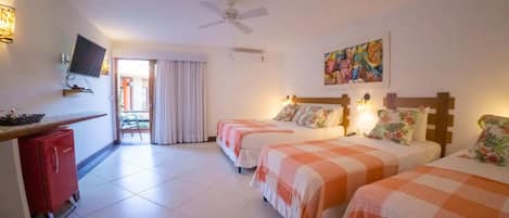 A hotel room with two beds, a desk, a TV, and a ceiling fan.