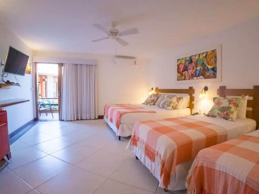 Une chambre d’hôtel avec deux lits, un bureau, une télévision et un ventilateur de plafond.