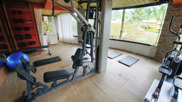 Academia com equipamentos de exercício, um banco e uma bola azul para ginástica.