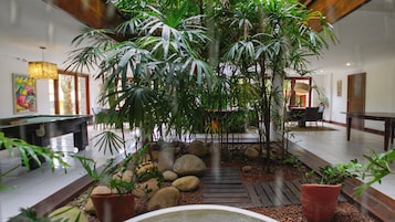Un vestíbulo con una fuente central, rodeado de plantas tropicales y rocas.
