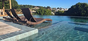 Una piscina cristalina con sillas de descanso y una terraza de madera.