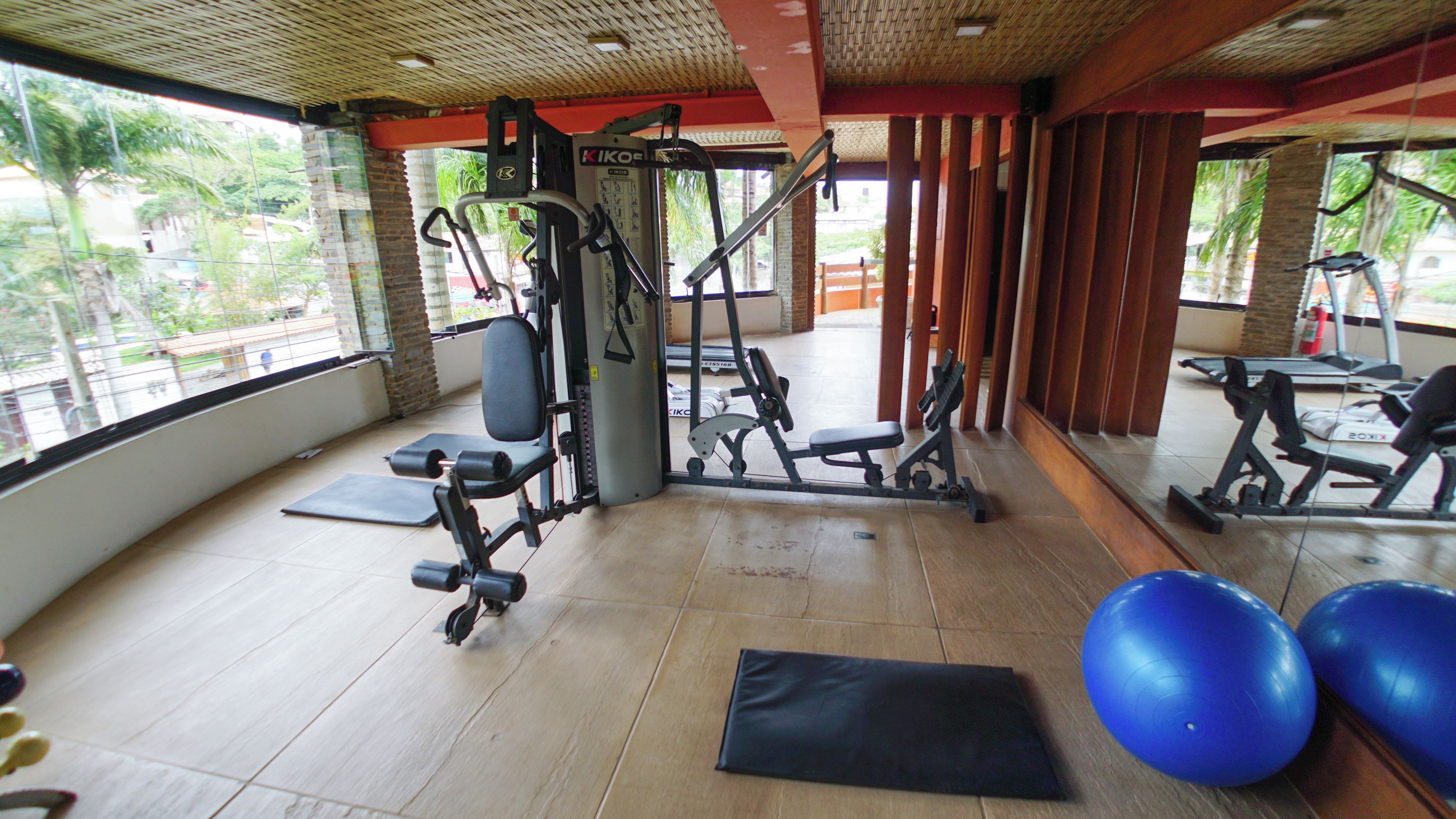 Un gimnasio con equipo de ejercicio, una colchoneta negra y pelotas de ejercicio azules.