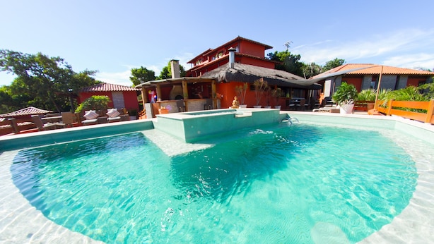 A large swimming pool with a thatched-roof structure in the background.