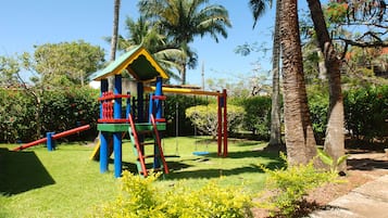 Explore a vibrant play area surrounded by lush greenery and a colorful play structure.