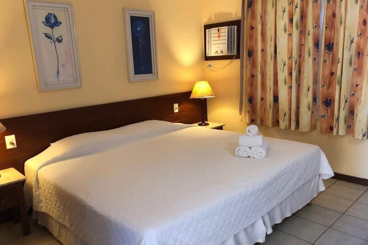 Habitación de hotel con una cama grande, una lámpara de noche, un panel de control en la pared y una cortina con estampado de pájaros.