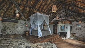 Una habitación rústica con suelo de piedra, una cama con dosel, chimenea y muebles de madera.