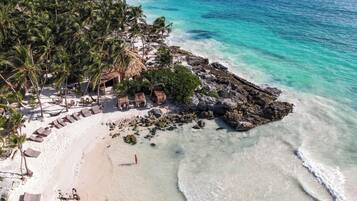 En la playa, playa de arena blanca, camastros y toallas de playa