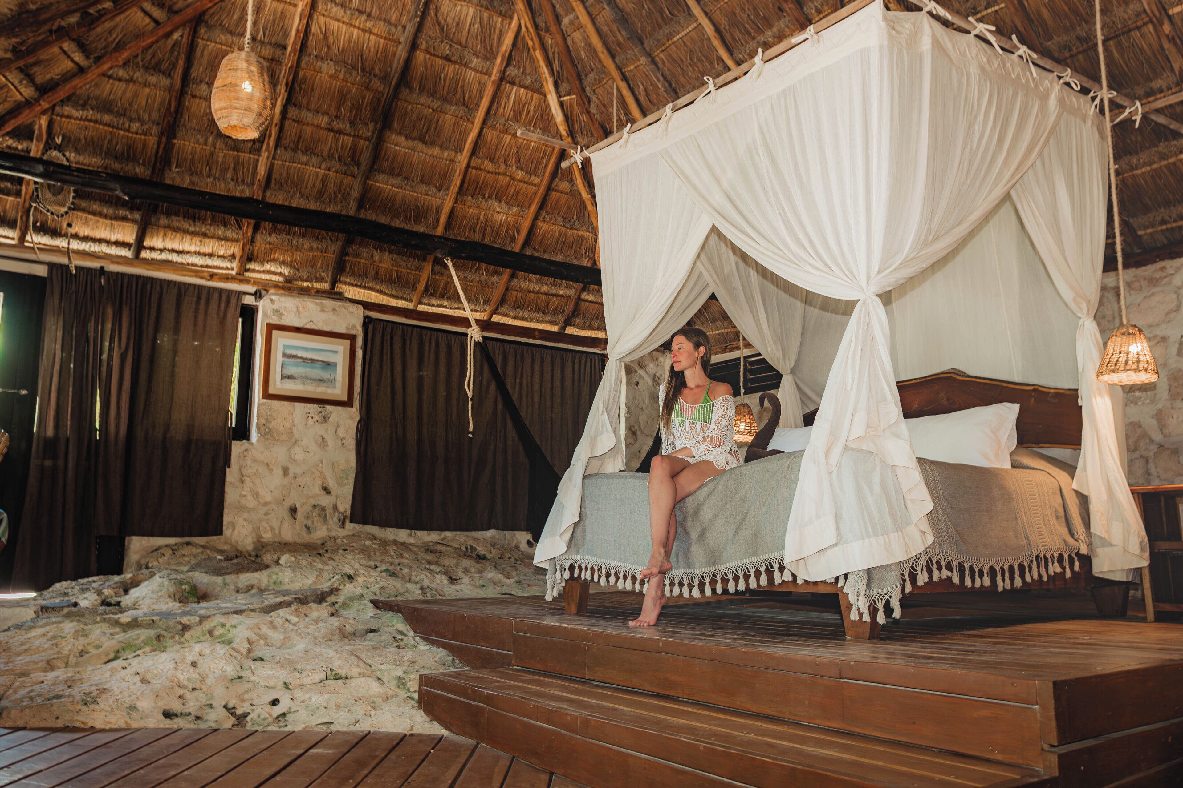 A bed with a canopy, wooden steps, and a stone wall.