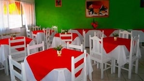 A dining area with white tables and red tablecloths, green walls, and ceiling fans. - Hotel Pousada Imperial (Porto Seguro)