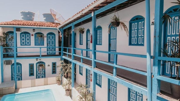 A building with blue-framed windows and doors, a tiled roof, and a pool area. - Hotel Pousada Imperial (Porto Seguro)