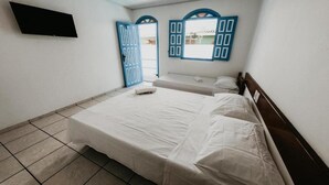 A bedroom with a single bed, a flat-screen TV mounted on the wall, and a window with blue shutters. - Hotel Pousada Imperial (Porto Seguro)