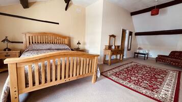 A bedroom with a wooden bed, a nightstand, a dresser, a mirror, a red patterned rug, and a sofa.