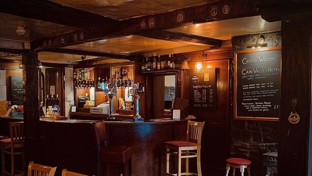 A cozy pub with wooden furniture, a bar area, and a chalkboard menu. - Cain Valley Hotel (Llanfyllin)