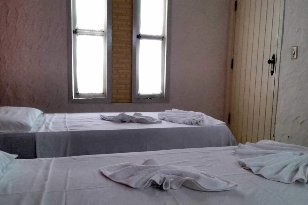 Ein Zimmer mit zwei Betten, einem Fenster und einem Kleiderschrank.