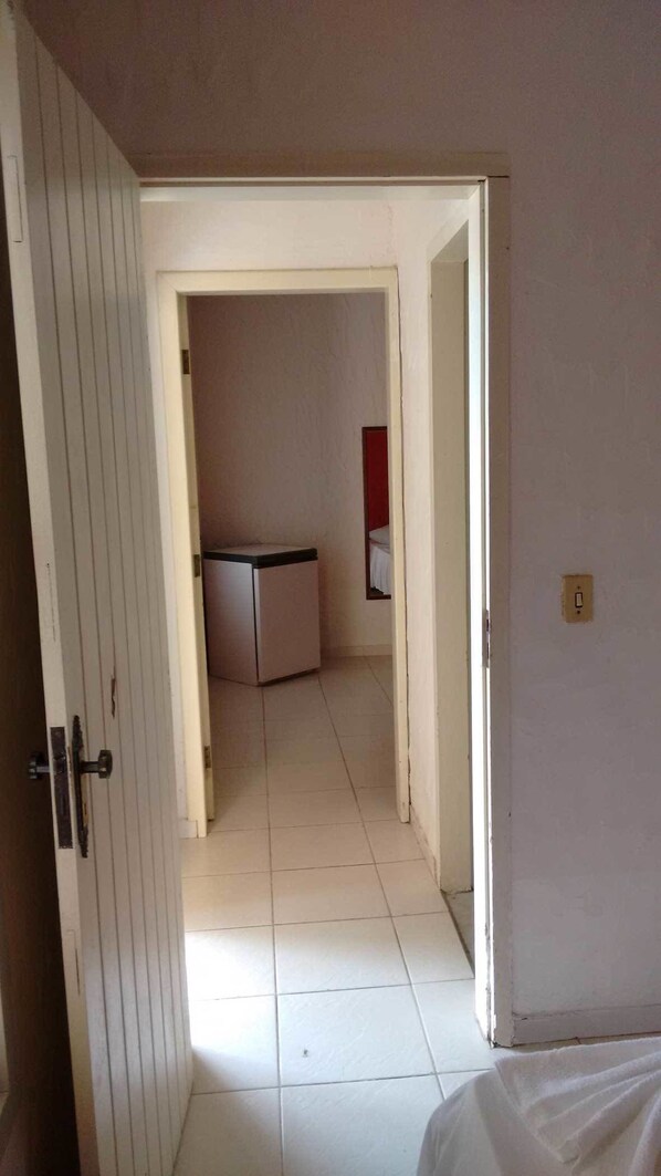 Un pasillo estrecho que desemboca en una pequeña cocina americana, con un refrigerador y una encimera.