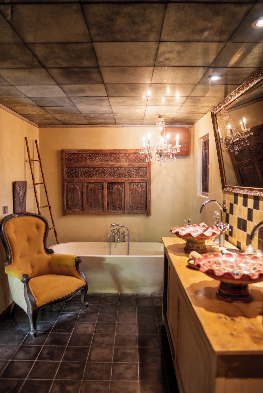 Un baño con bañera, tocador de madera con espejo, candelabro y una silla antigua.
