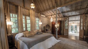 A spacious bedroom with a large bed, wooden ceiling, and large windows. - BALQUISSE Heritage Hotel (Jimbaran)