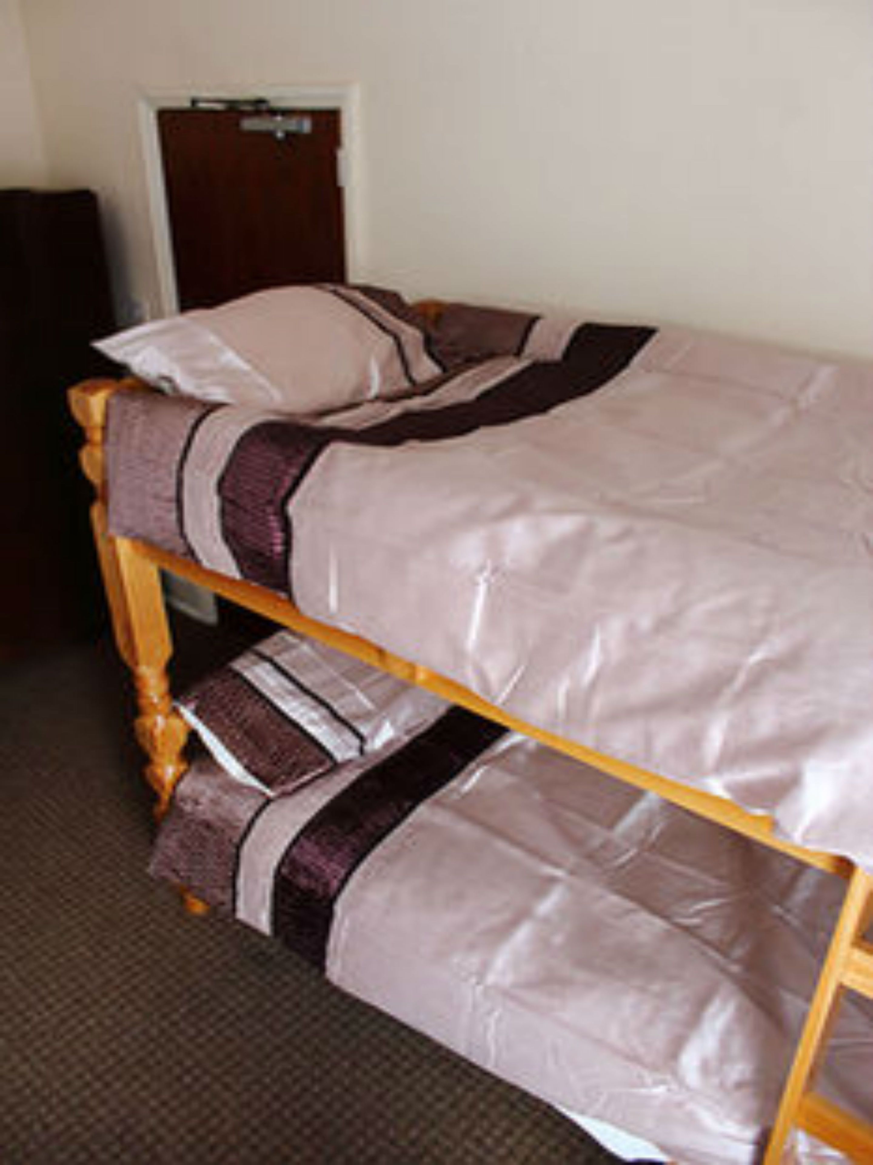 A single bed with a wooden frame and a white mattress.